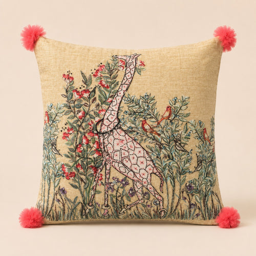 Blossom Giraffe cushion — pink line-drawn giraffe among flowering branches on oatmeal linen with coral pom-poms, flat catalogue