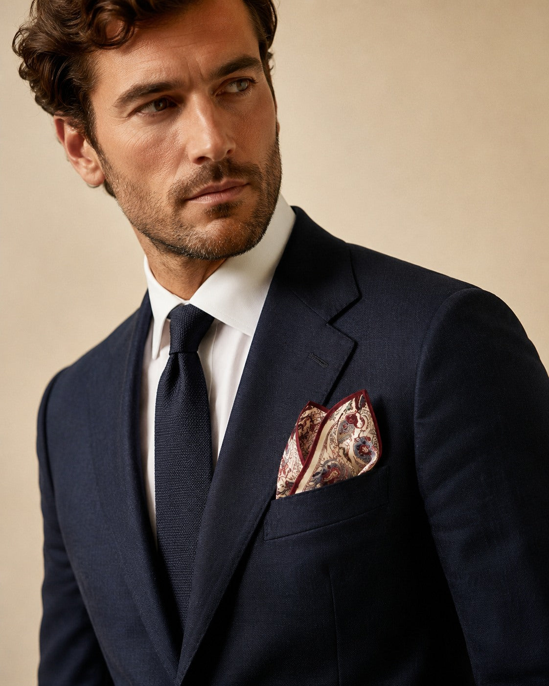 Male model wearing the Jacobean Paisley silk pocket square folded in a navy suit breast pocket