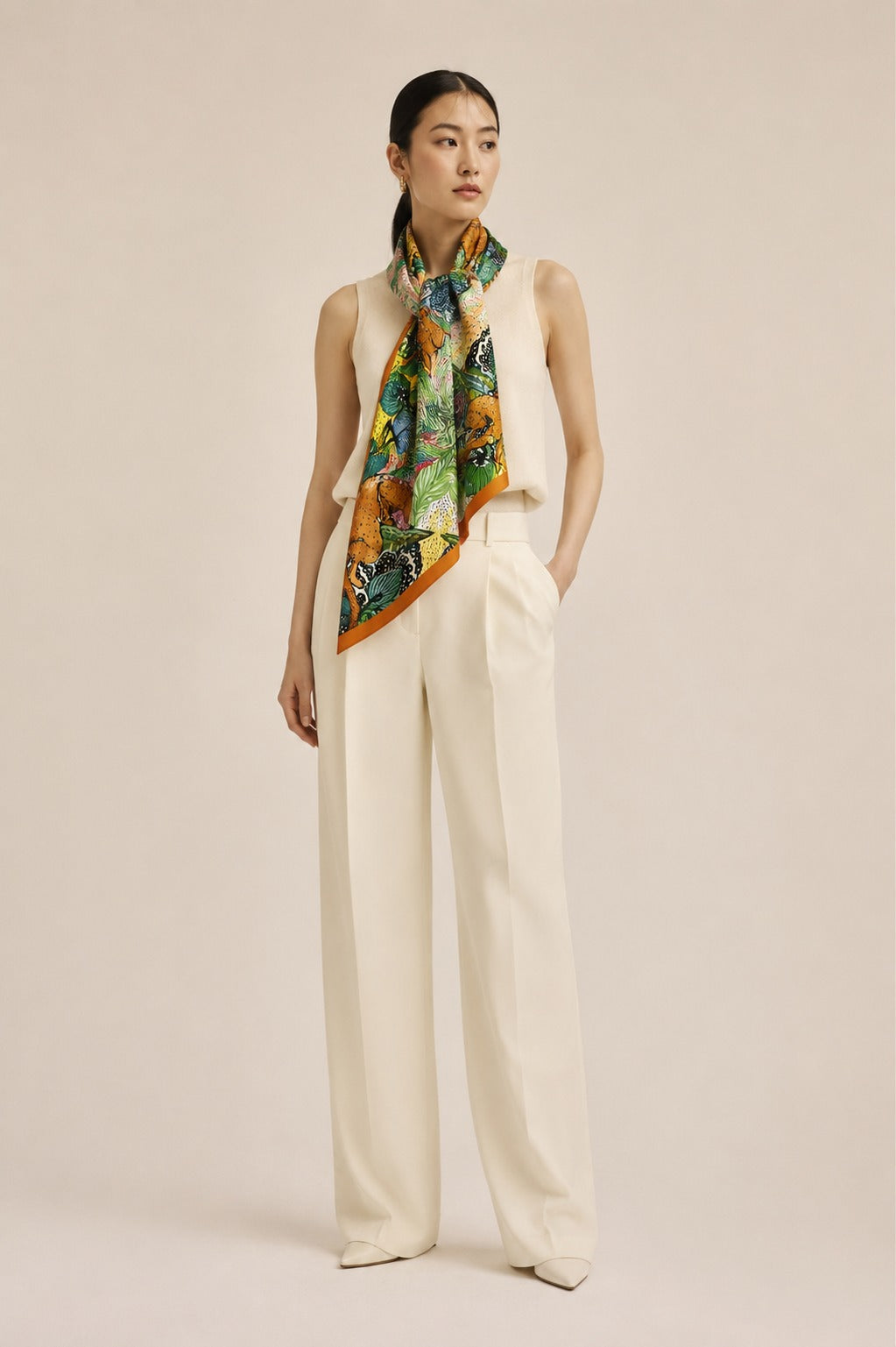 Model wearing the Jungle Caracal silk scarf knotted at the neck with cream tailoring