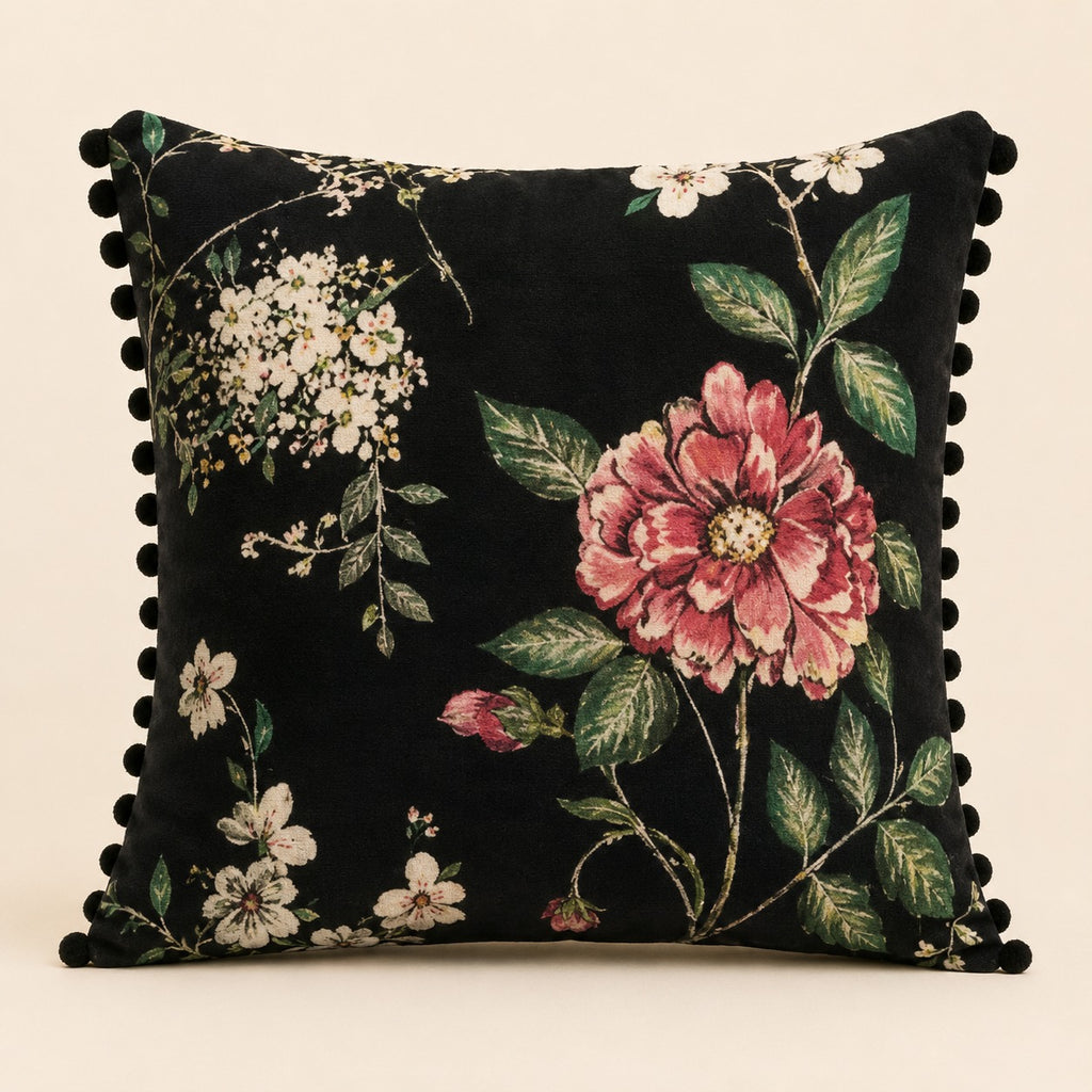Night Rose cushion — a single pink rose and white blossom on black with black pom-poms, flat catalogue
