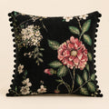 Night Rose cushion — a single pink rose and white blossom on black with black pom-poms, flat catalogue