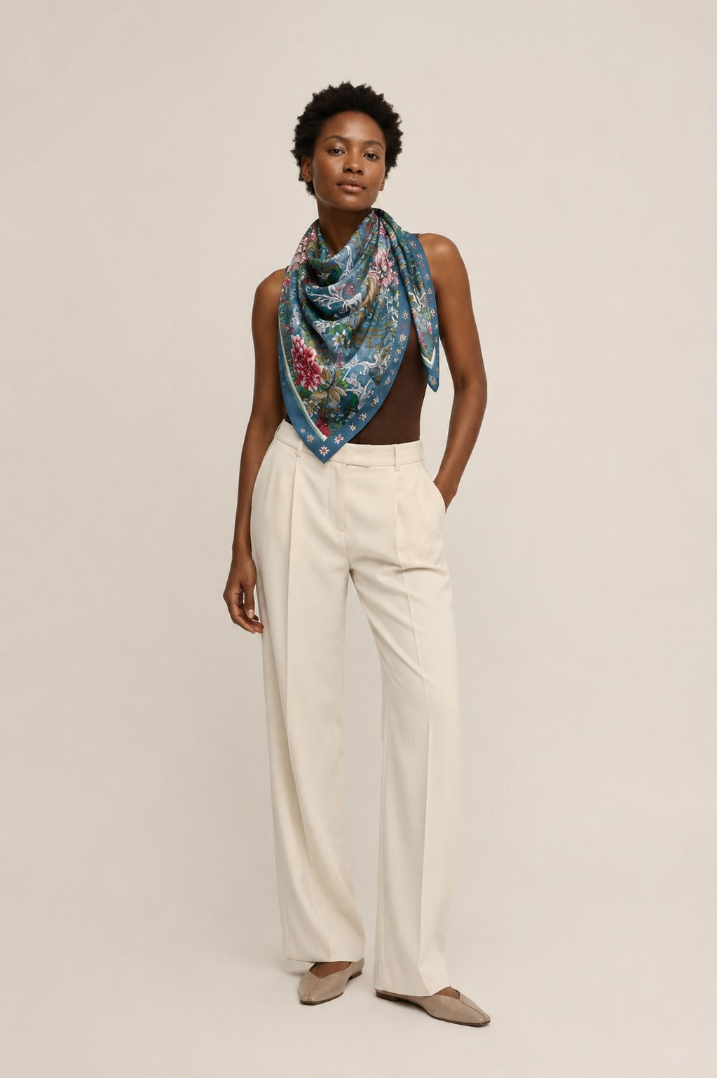 Model wearing the Songbird Chintz silk scarf draped at the neck with cream tailoring