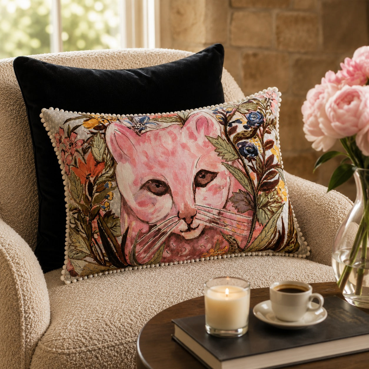 Wildflower Cat Cushion styled on a cream armchair beside pink peonies